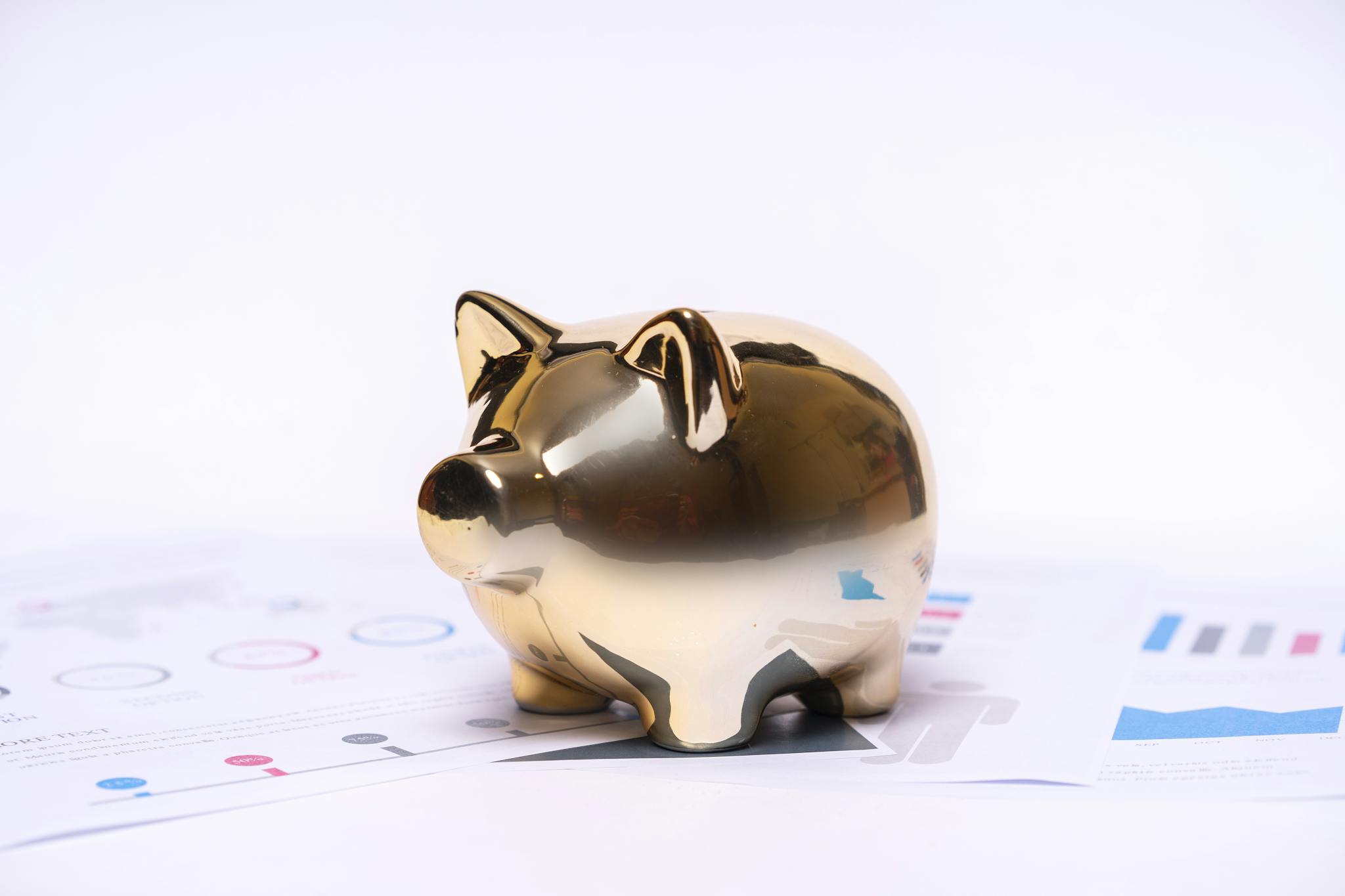 Close-up of a golden piggy bank on financial documents, symbolizing savings and investment.